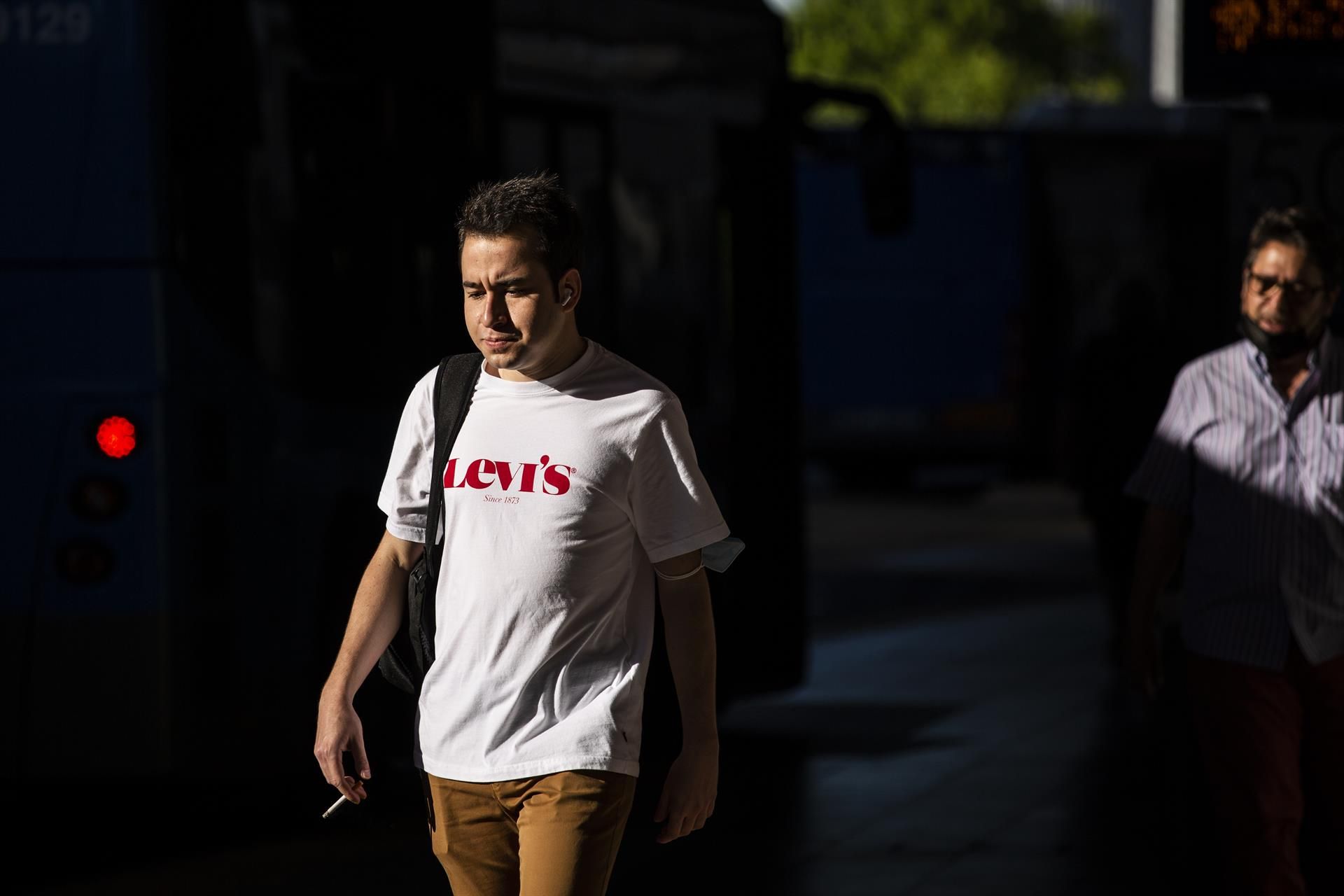 Un joven camina sin mascarilla y fumando