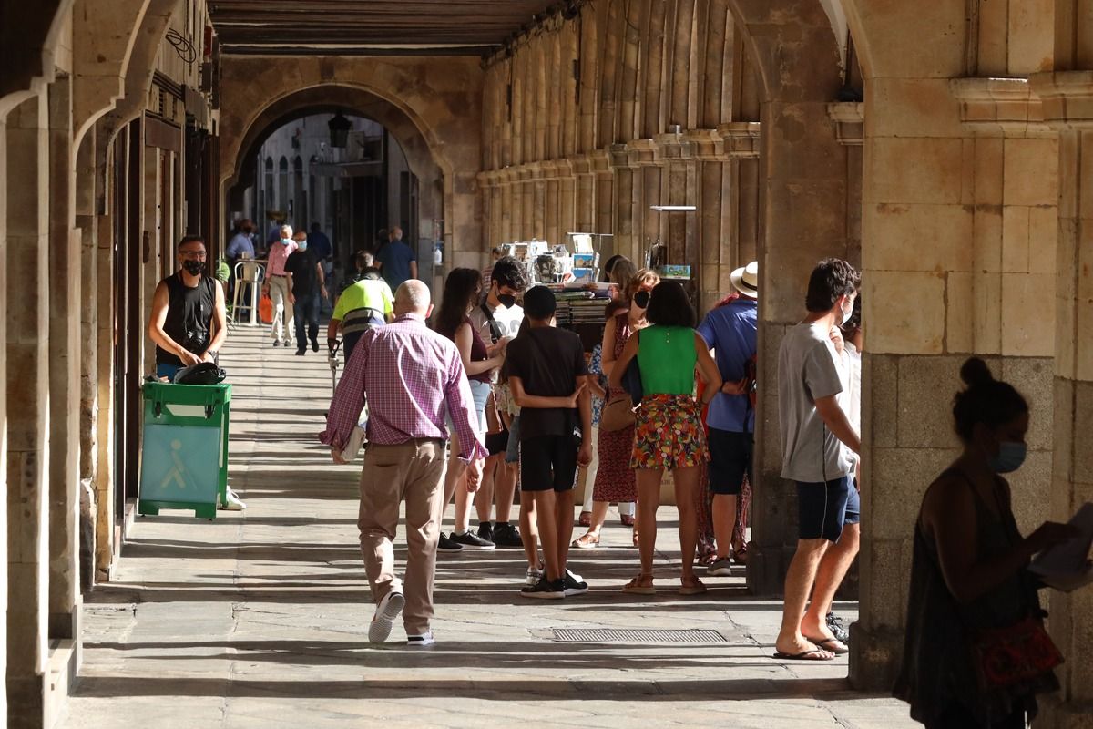 Salmantinos y turistas pasean por los soportales de la Plaza Mayor