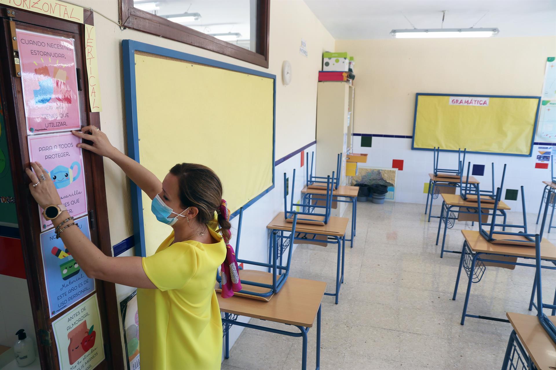 Una profesora coloca carteles de medidas preventivas ante el COVID 19 en el aula | Fotografía EP