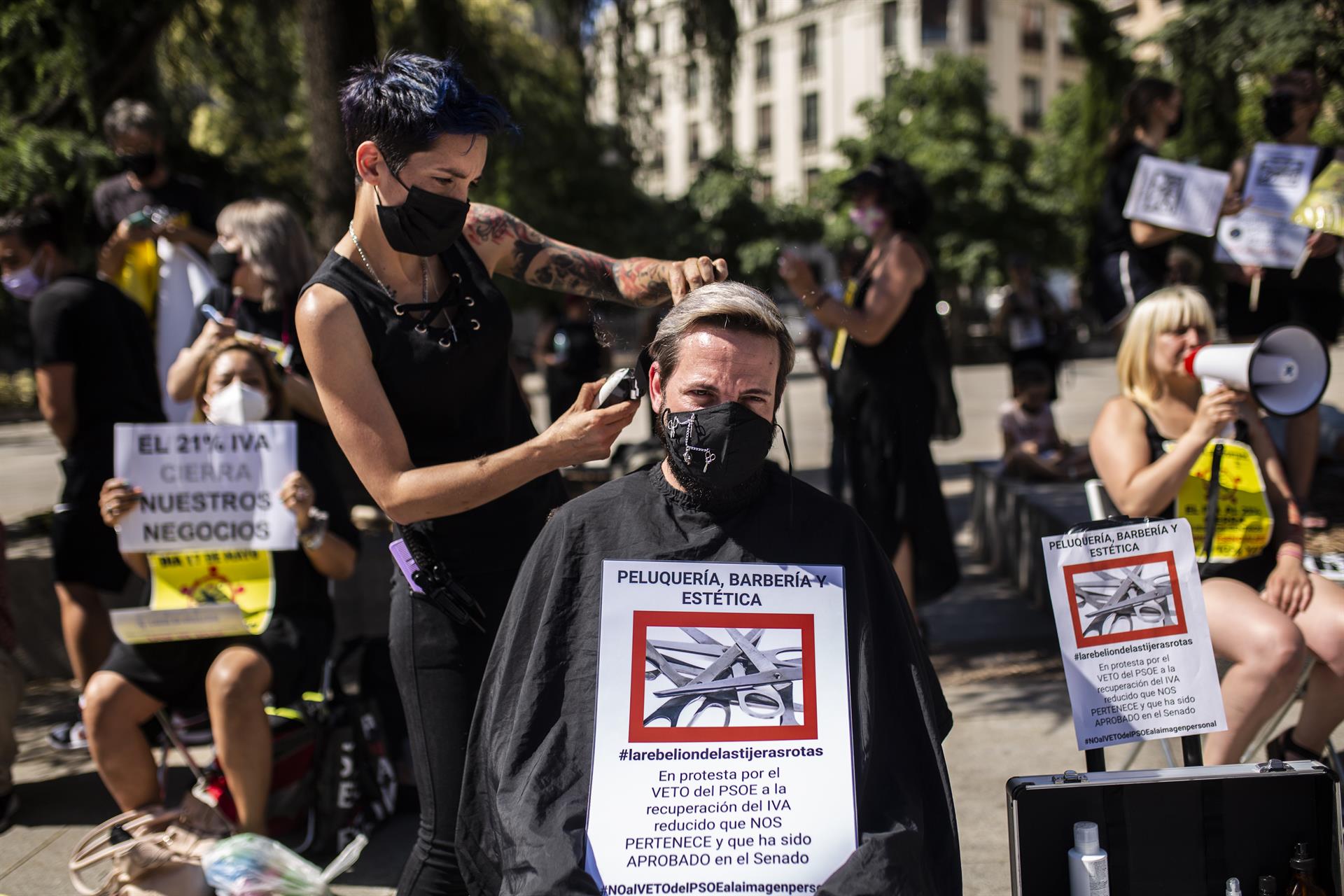 Una peluquera corta el pelo a un hombre durante una protesta frente al Congreso de los Diputados para exigir el IVA reducido. Ep