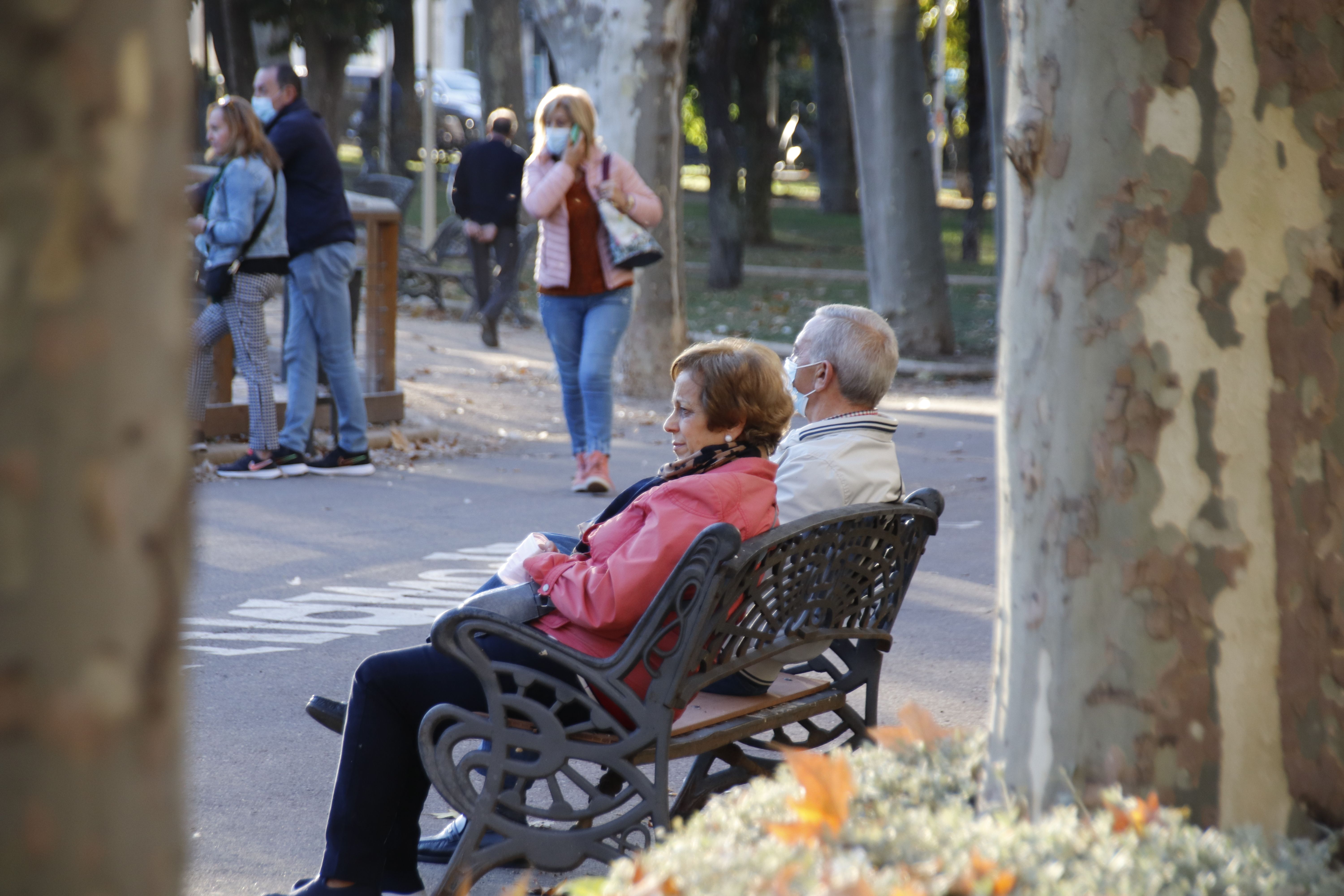 Personas mayores en un banco de Alamedilla en otoño