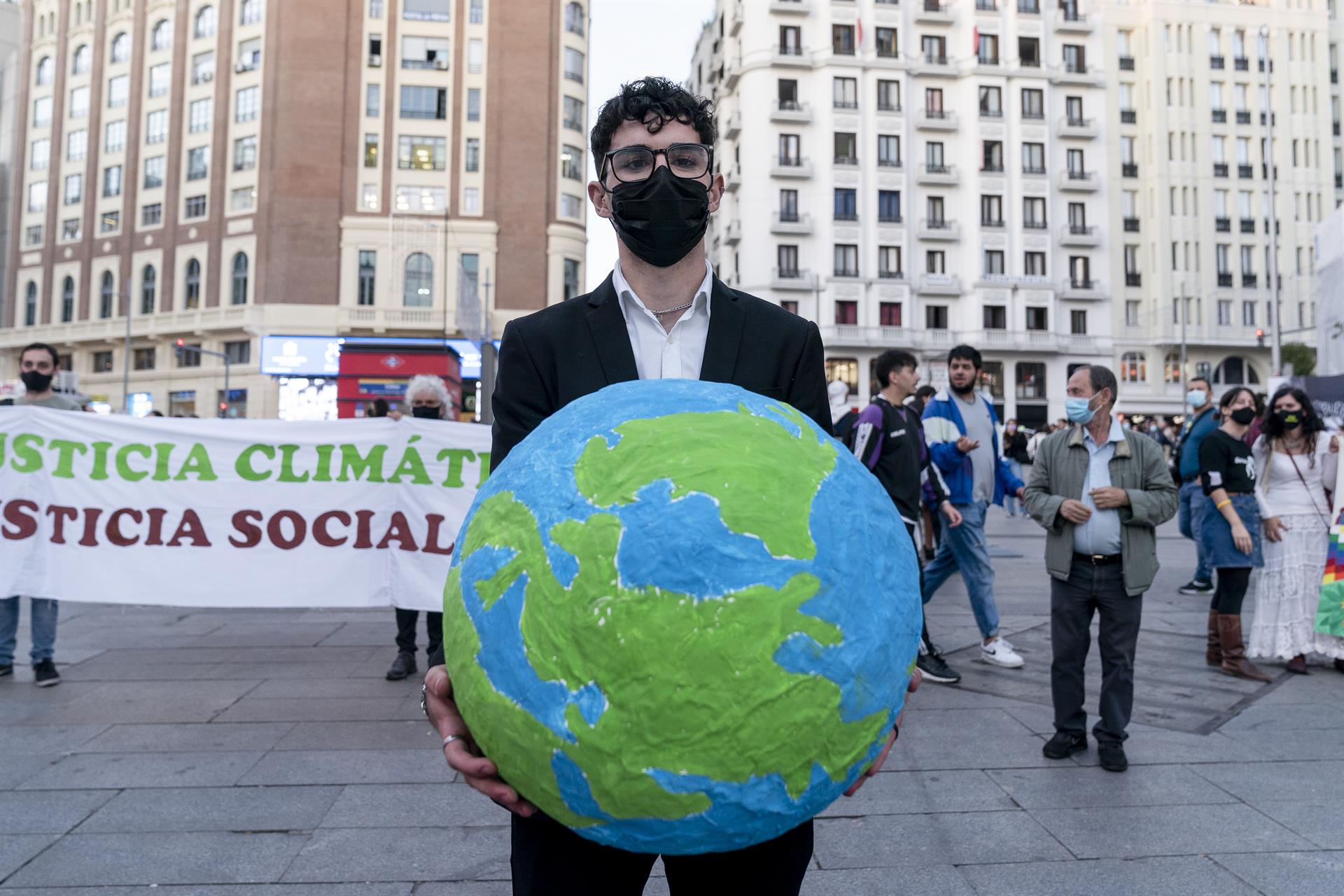 Un hombre con una bola del mundo en una concentración bajo el lema ‘No habrá justicia climática sin justicia social’ en Callao, Madrid(España). Foto EP.