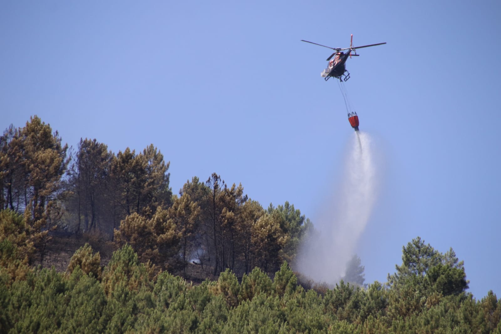 Helicóptero descarga agua sobre un incendio. Foto de archivo