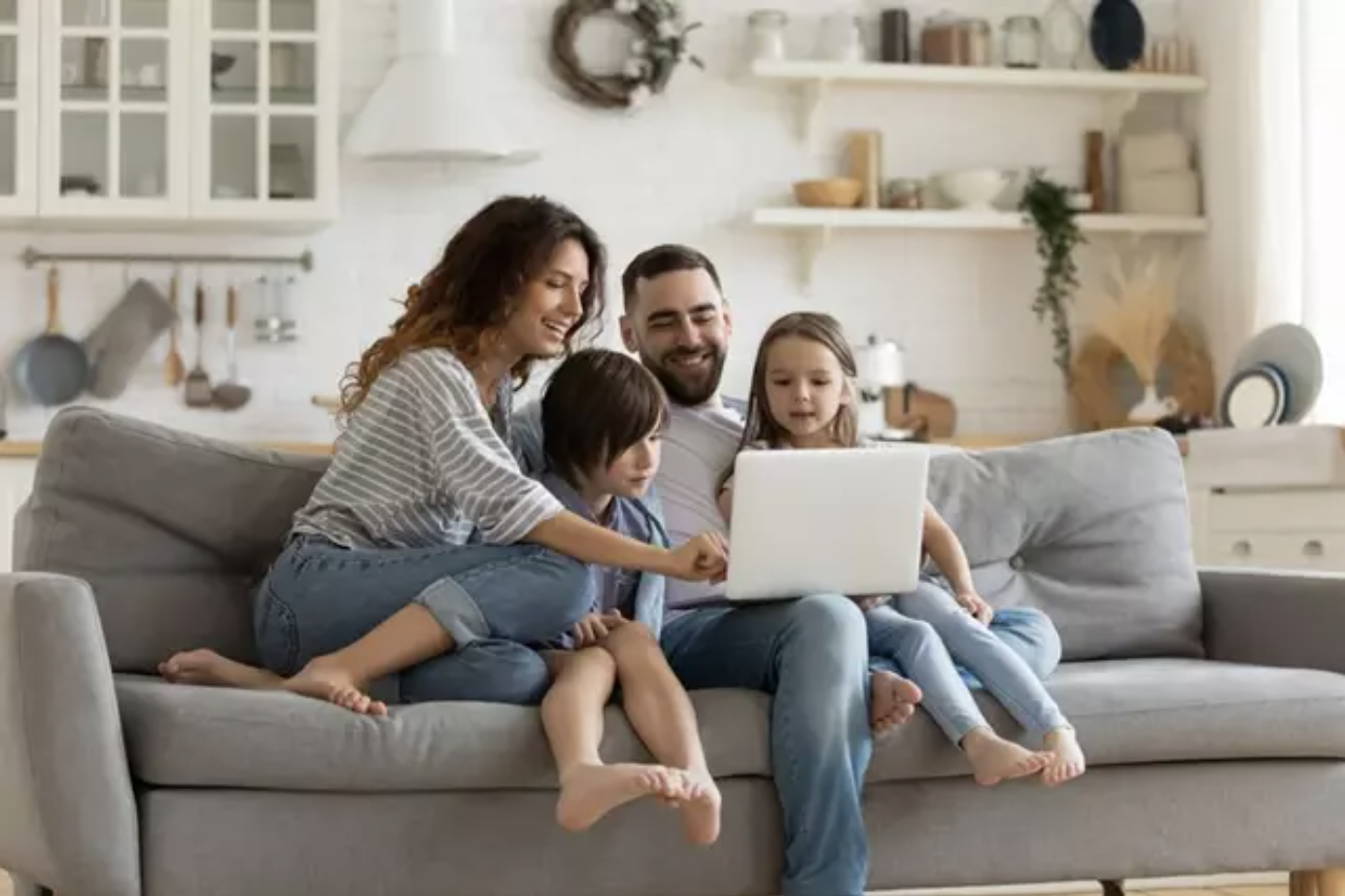 Familia feliz en casa mirando un ordenador - ISTOCK