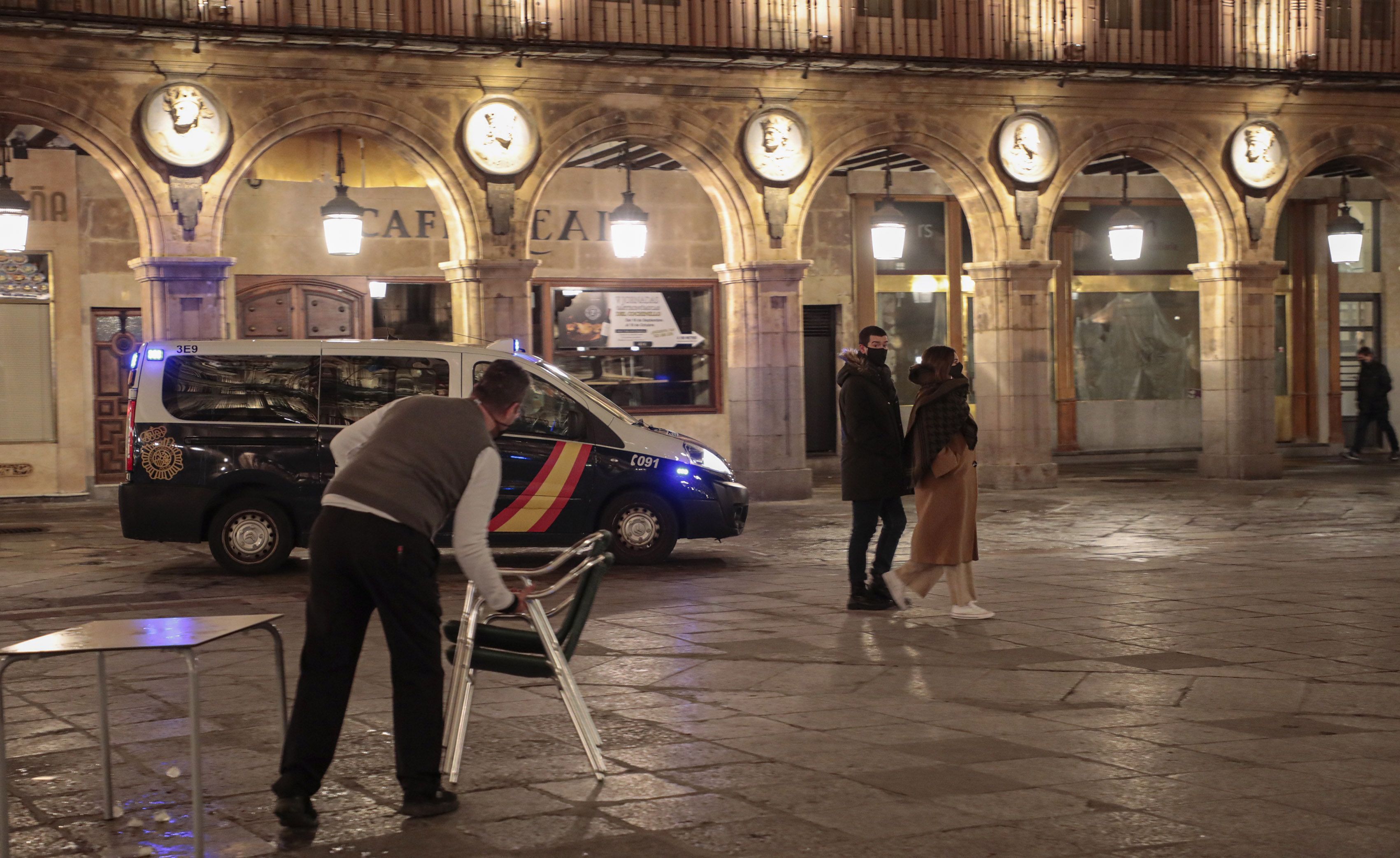 Un hostelero recoge una terraza en la Plaza Mayor minutos antes de iniciarse el toque de queda de las 20 horas en la Plaza Mayor. | FOTO: ICAL